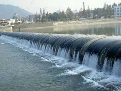 A black water inflatable rubber dam has overflow in a long span river.