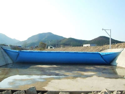 A blue inclined bookend rubber dam is in the no water river.