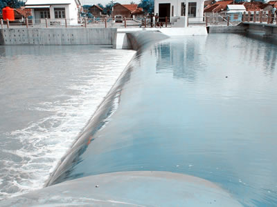A inclined light blue water inflatable rubber dam has overflow.