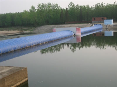 A blue water inflatable rubber dam is under the pier and water level is low.
