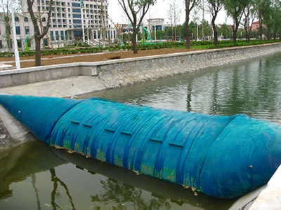 A blue spoiler rubber dam is in the river which water level is low.