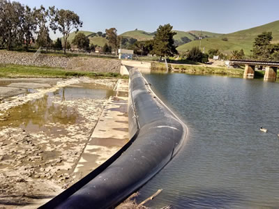 A black bookend rubber dam is in front of the bridge to retain water.