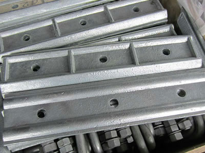 Galvanized clamping plates and anchor bolts with screw nuts are in the wooden box.