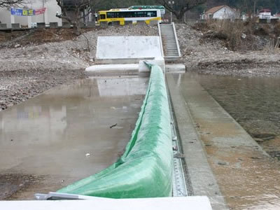 A green bookend rubber dam is in the river which water level is low.