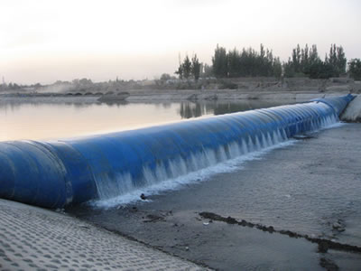 A blue inclined water inflatable rubber dam has overflow and upstream has high water level.