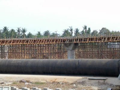 Black air inflatable rubber dam is in front of the bridge which is in construction.