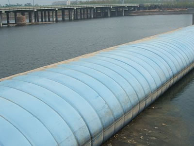 Light blue air inflatable rubber dam has many vertical grains in the water.