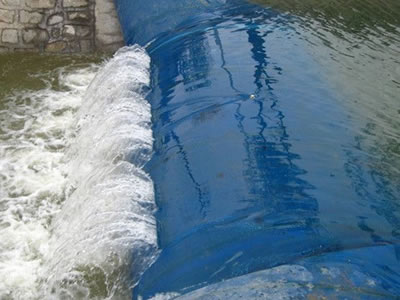 The water overflows the spoiler rubber dam and forms a waterfall.