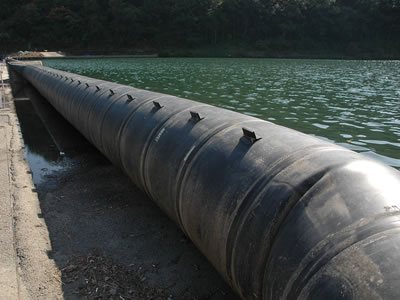 A black spoiler rubber dam is on the side of the river.
