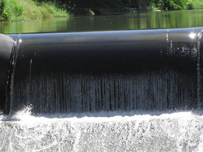 A narrow black water inflatable rubber dam has overflow.